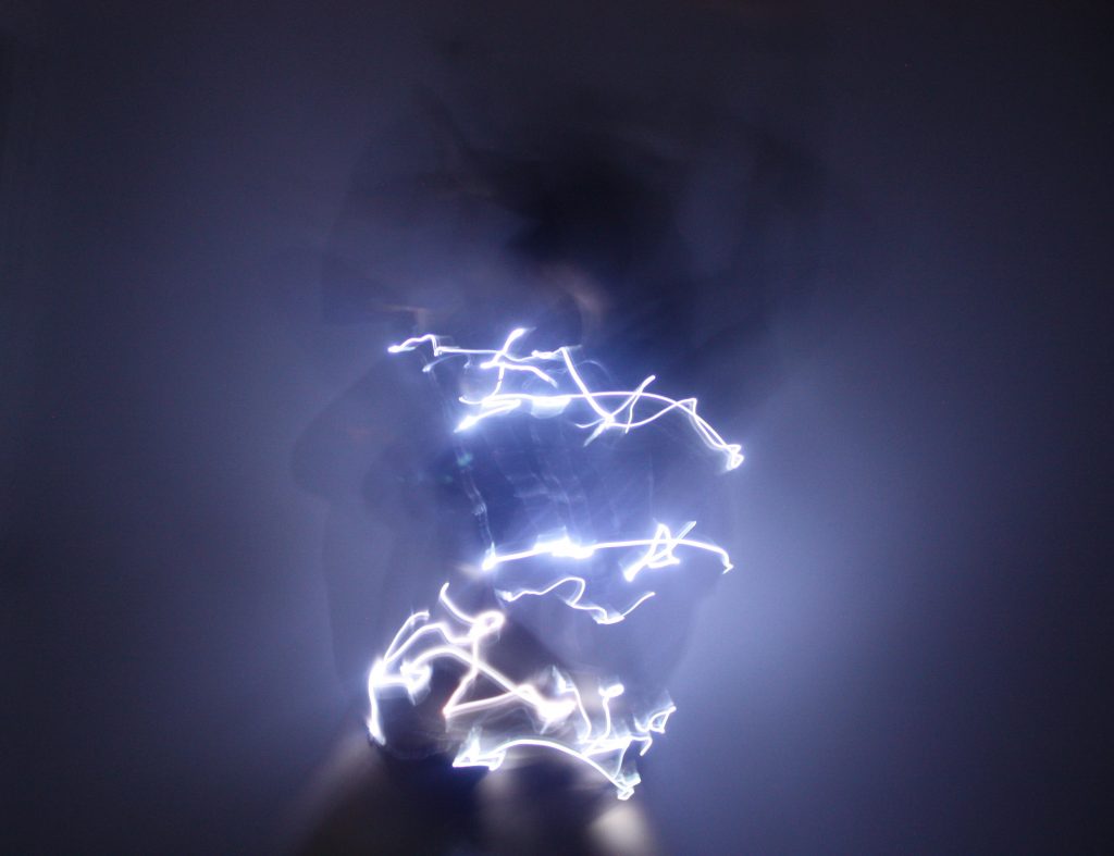 Amirah Ijaiya - Blurred lines of white light around a body in motion in a dark space