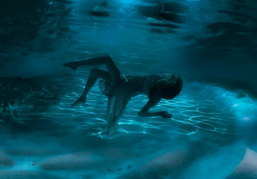 April Chapman - A person floating under darkened water