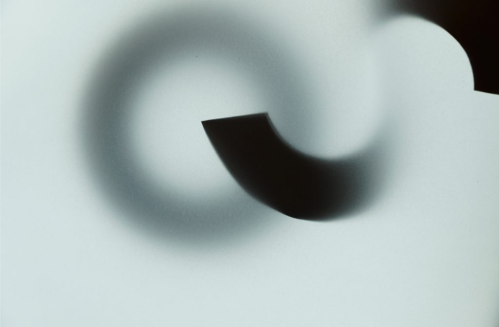 Evie MacCallum - Twisted black shapes and dark circular shadows on a grey background