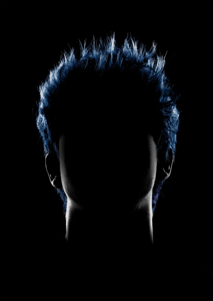 Gabriel James - Portrait of a person with short spiky hair on a black background, with only the face outline in light