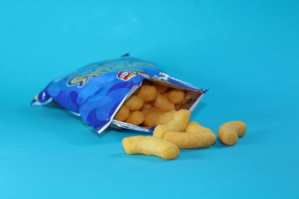 Olivia Pigott-Read - A bag of Wotsit crisps spilling out of the bag onto a pale blue backdrop