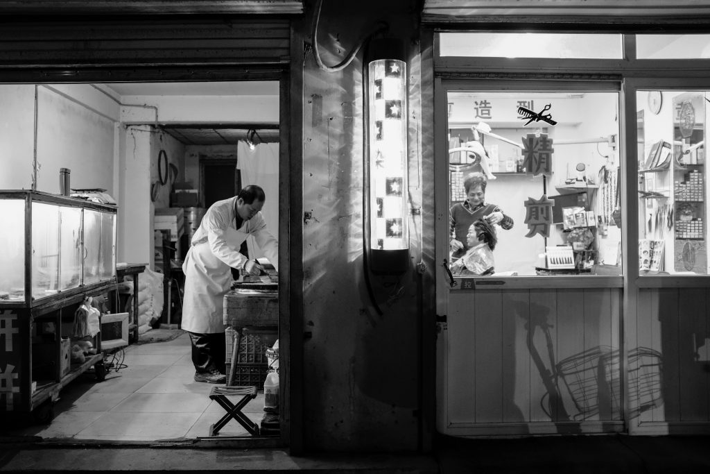 Yuhan Song - Monochrome image looking into two small Asian shop entrances with staff at work
