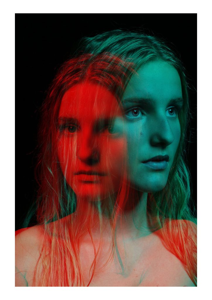 Ella Martin - Double exposure portrait of a young woman in blue and red light against a black backdrop.