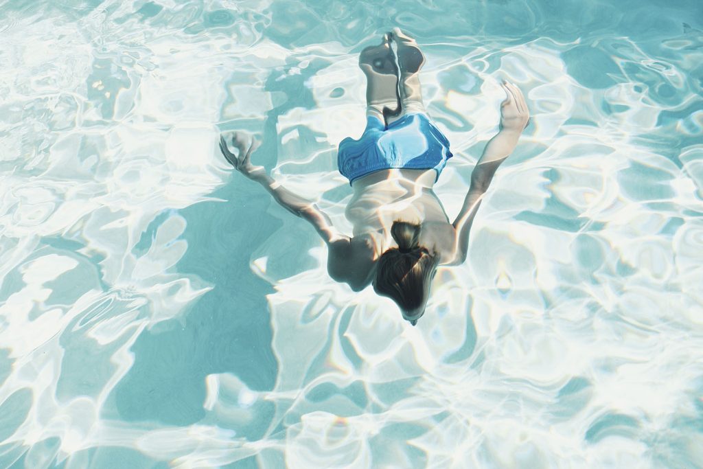 Freya Carlton-Smith - Image of a person swimming in a clear blue pool, taken from above.