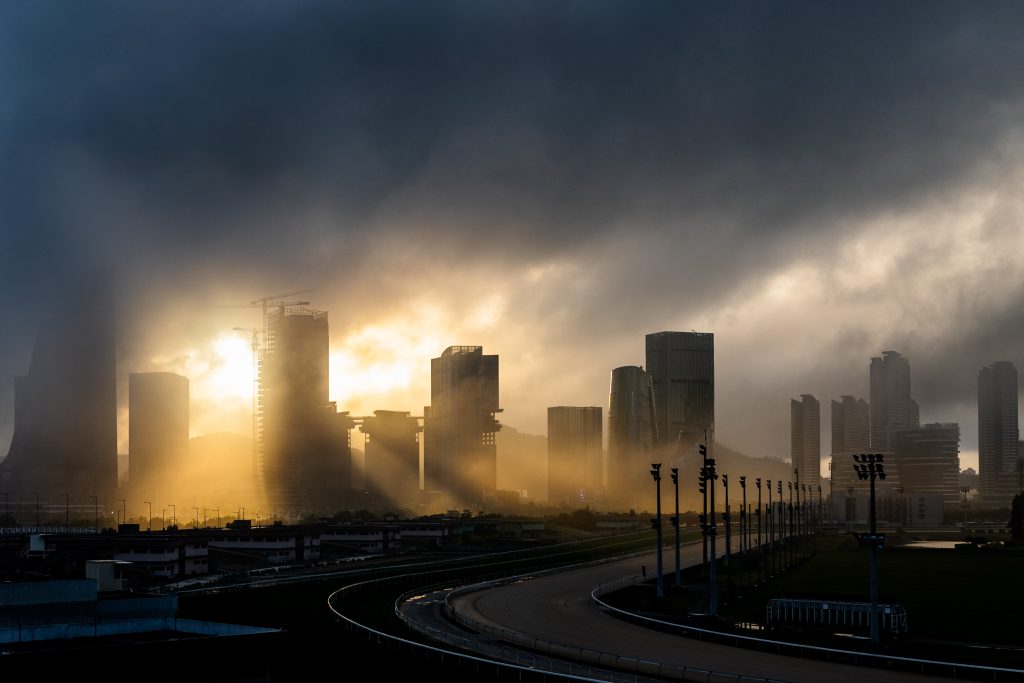 Housam Yeung - Sunlight streams through dark clouds and high rise buildings.
