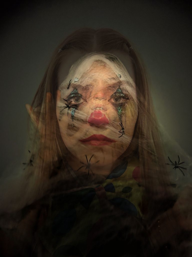 Ophelia Dryhurst - Portrait of a girl with long blonde hair wearing dark clown makeup.
